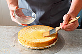 Swiss Zug cherry cake being made: a sponge base being brushed with liquid