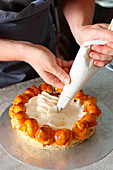A Saint Honore cake being made: vanilla cream being piped on
