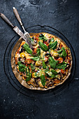 Glutenfreie, vegane Blumenkohl-Pizza mit Tomaten, Pilzen, Spinat und Käseersatz