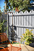 Outdoor shower on the fence in the sunny garden with terrace