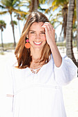 A brunette woman outside wearing a white blouse