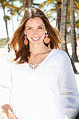 A brunette woman outside wearing a white blouse