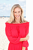 Blonde Frau in rotem Kleid am Strand