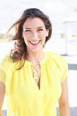 A young woman wearing a yellow sleeveless top