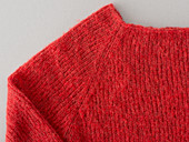 A red, hand-knitted raglan jumper