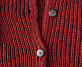 A red, hand-knitted cardigan with a button placket