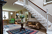Antique furniture and white staircase in spacious foyer