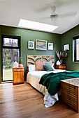Schlafzimmer in Naturtönen mit grünen Wänden und Blick auf Bäume