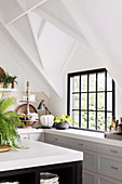 Küche unter weißem Giebeldach mit schwarzen Sprossenfenster und Kücheninsel