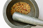 Curry powder – roasted nuts, sesame seeds and herbs being crushed in a mortar