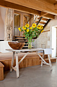 Wooden bowl and vase of sunflowers on table in converted barn