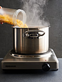 Pasta being poured into a pot of boiling water