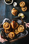 Child holding tray with variety of homemade puff pastry buns, cinnamon rolls and croissant