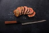 Sliced grilled meat barbecue Steak and kitchen Knife on black background