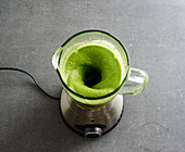 A green smoothie being made in a blender