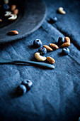 Blueberries, almonds and cashews on a blue tablecloth