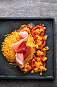 A potato and celeriac fritter with a tomato salad and ham