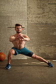A young man performing a strength exercise in a side lunge