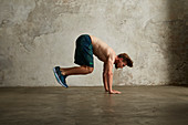 A young man doing a tuck jump from a push-up position