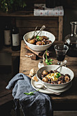 Traditional Boeuf Bourgingnon dish served with pasta side in bowls on wooden table