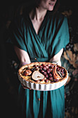 A woman serving a cheese quiche with pears and grapes