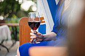 A woman sitting in a beach chair with a glass of red wine