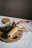 Dry corn and jar with brown spice cubes placed on wooden board on table