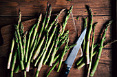 Green asparagus with a knife on a wooden surface