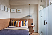 Striped pillows on double bed against walls upholstered in leather