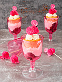 Layered desserts with raspberries, quark cream, cupcakes and flamingo decorations