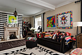 Ziffernblatt-Teppich vor schwarzem Sofa mit farbenfrohen Designer-Kissen