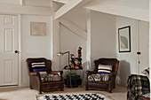 Two vintage, brown leather armchairs in attic room with white wood-beamed ceiling