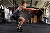 Junger Mann bei Fitnessübung Deck Squat