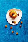 Various types of tomatoes on a plate against a blue background