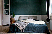 Double bed against dark wall with white wooden wainscoting