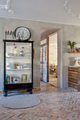 Crockery in glass-fronted cabinet with large clock on top