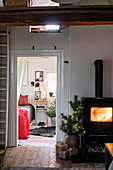 Roaring fire in wood-burning stove and view into bedroom