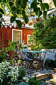Nostalgische Gartenmöbel auf Holzterrasse in idyllisch sommerlichem Garten