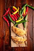 Empanada Patties between green plant and chili pepper