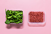 Minced meat and spinach leaves in storage containers