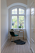 Delicate golden desk below arched window in period building