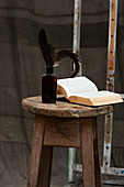 Aufgeschlagenes Buch und Flasche mit Feder auf Holzhocker