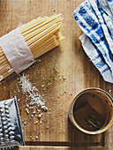 Ungekochte Spaghetti, Reste von Kräutern und Reibekäse und leere Konservendose