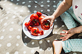 A plate of various tomatoes with a child taking one