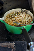 A pan of beans with rosemary on a hot plate