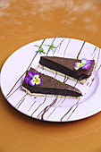 Two pieces of chocolate tart with horned violets