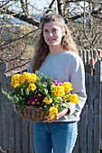 Woman carries basket of primroses and rosemary
