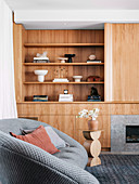 Built-in wooden wall unit in the living room with gray sofa