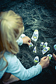 Girl playing with painted pebbles in sand