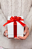 Hands of woman holding Christmas present with candy cane